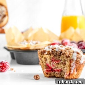 Cranberry Orange Muffin with a bite taken out, revealing its fluffy layers and fruit distribution.