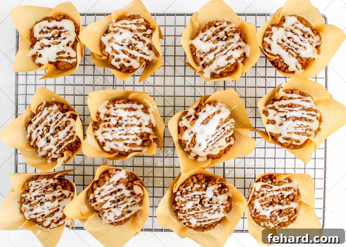 Best Cranberry Orange Muffin Recipe Cranberry Orange muffins with glaze drizzled on top, resting on a cooling rack.