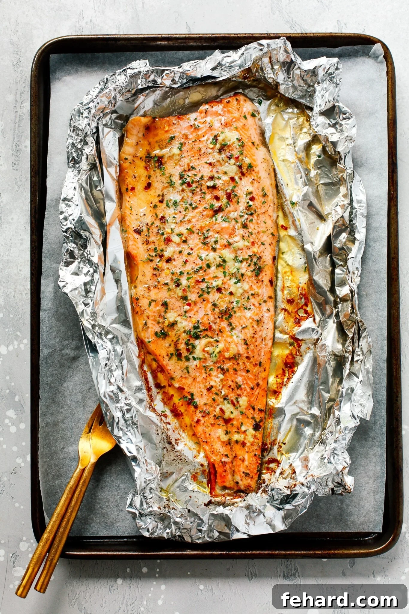 Mouthwatering Garlic Butter Rainbow Trout 2 Overhead view of a perfectly cooked Garlic Butter Rainbow Trout fillet on a baking sheet, ready to serve.
