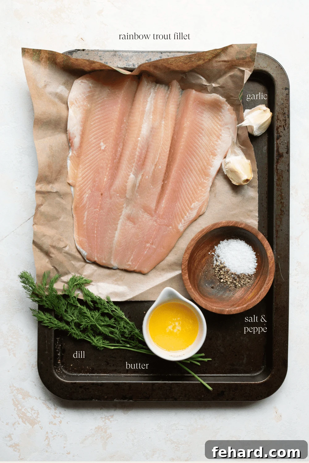 Mouthwatering Garlic Butter Rainbow Trout 3 Overhead view of fresh ingredients laid out for making the rainbow trout recipe, including fillets, butter, dill, and garlic.