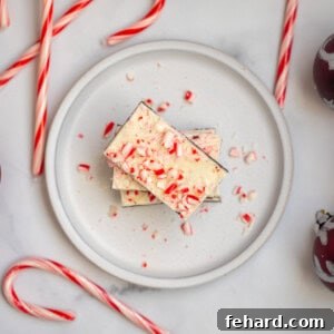 Peppermint Bark on plate stack up with candy canes in background.