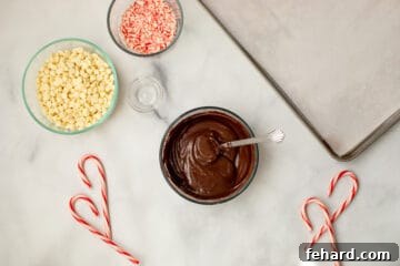 Melted chocolate next to sheet pan lined with parchment paper and candy canes.