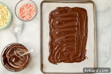 Melted dark chocolate spread out on sheet pan in a 9x13 inch rectangular shape.