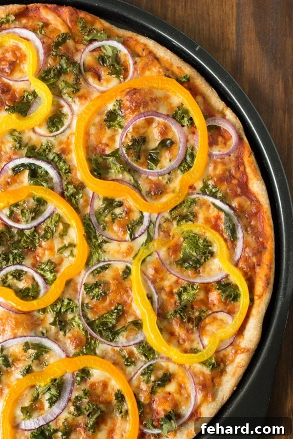 Close up of a freshly baked Kale, Peppers, and Red Onion Pizza with crispy crust and melted cheese
