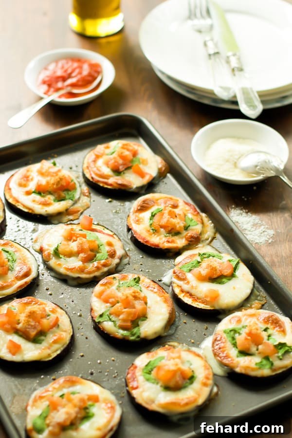 Close-up of baked Eggplant Pizza Bites topped with cheese and herbs