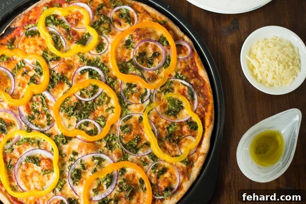 A whole Kale, Peppers, Red Onion Pizza in a round pan, with a rustic look and olive oil drizzled