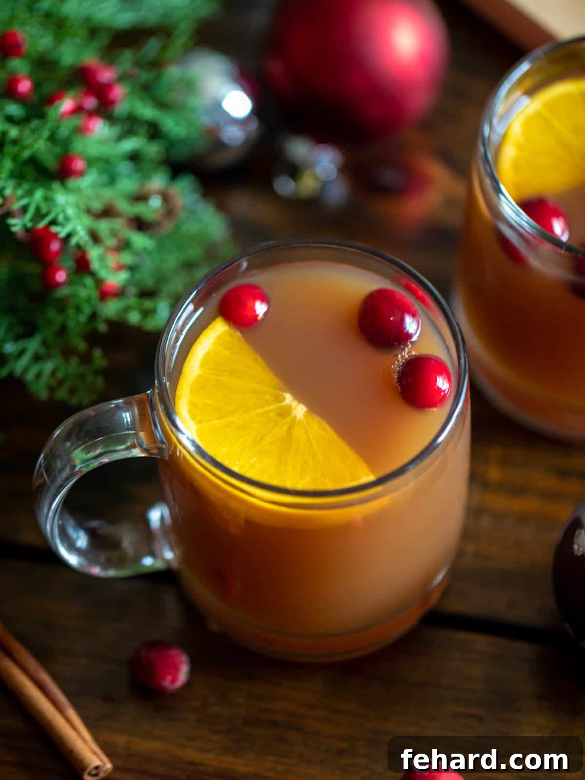 Christmas Tea Christmas Tea served up in elegant glass mugs, garnished with cinnamon sticks and fresh cranberries, with a soft festive background.