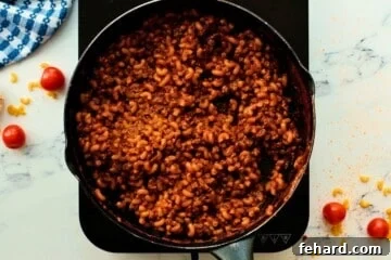 Tender homemade hamburger helper with macaroni noodles simmering in a skillet.