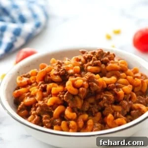 Hamburger Helper with macaroni noodles dished up in white bowl, ready to be served.