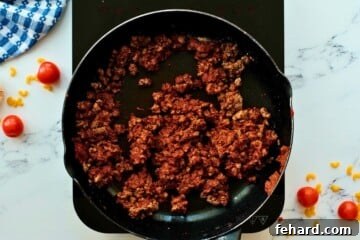 Ground beef, tomato paste, and spices cooking in a skillet for homemade hamburger helper.