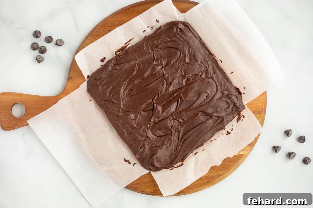 A large block of perfectly set fudge resting on parchment paper, awaiting its final transformation into delicious, bite-sized slices.