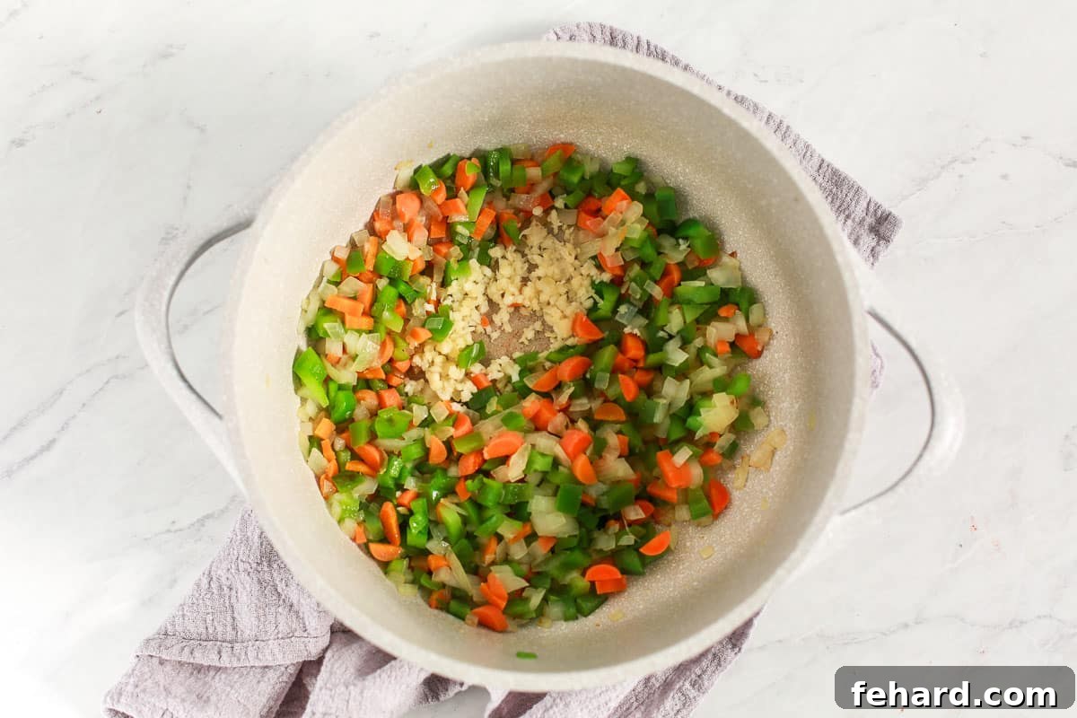 Uncooked vegetables being sautéed in a soup pot.