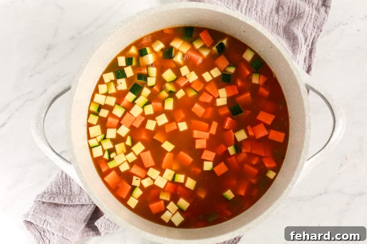 Vegetables and broth simmering in a soup pot.