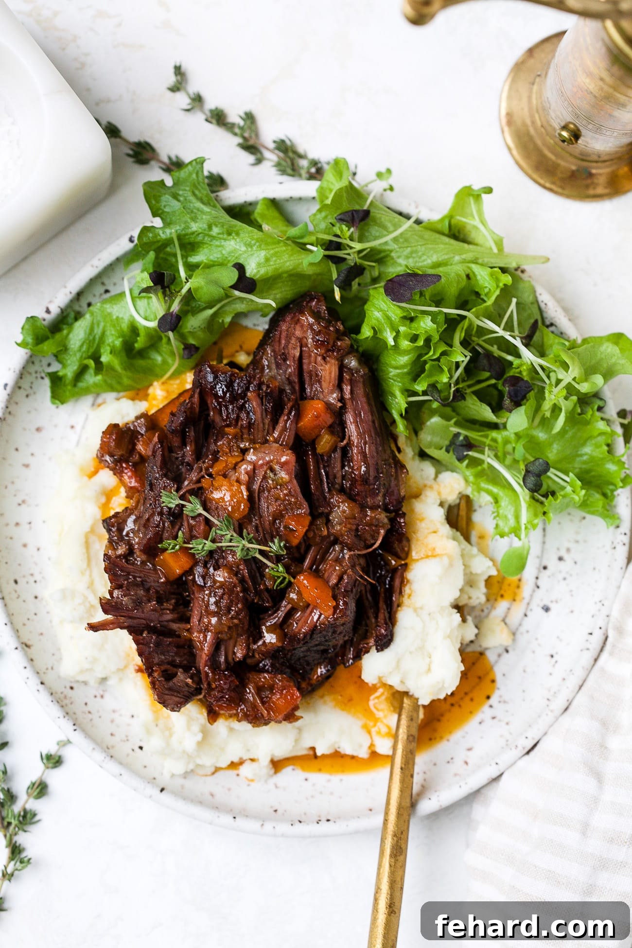 Red wine braised short ribs on a plate with mashed potatoes and salad. 