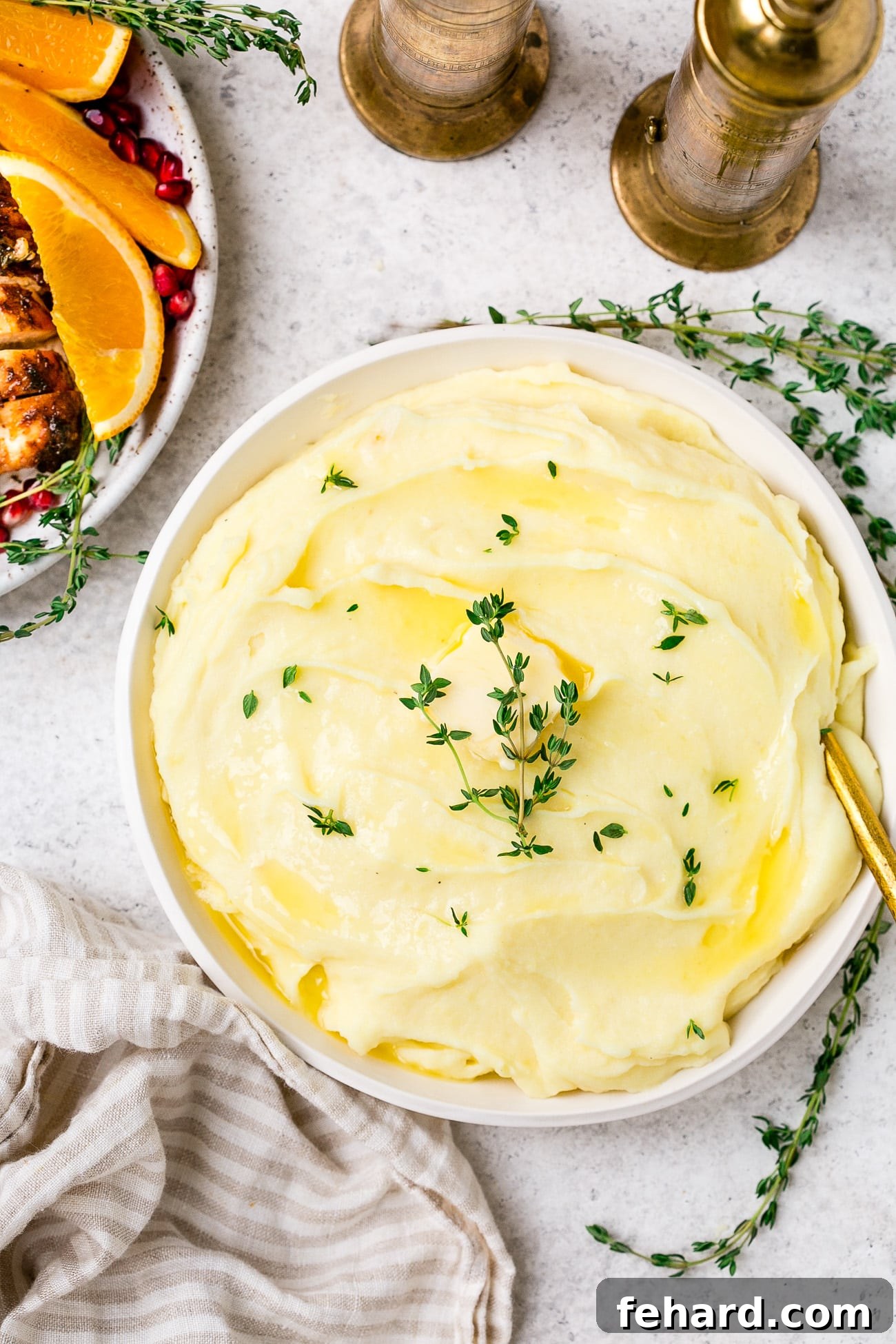 A beautiful serving dish overflowing with golden-brown roasted garlic mashed potatoes, garnished with fresh thyme. The texture is visibly creamy and inviting.