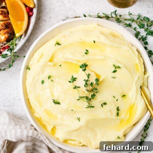 A close-up of creamy Roasted Garlic Mashed Potatoes in a bowl, garnished with fresh thyme.