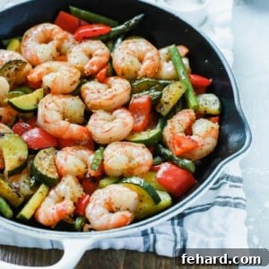 A white cast iron with shrimp and vegetables inside.