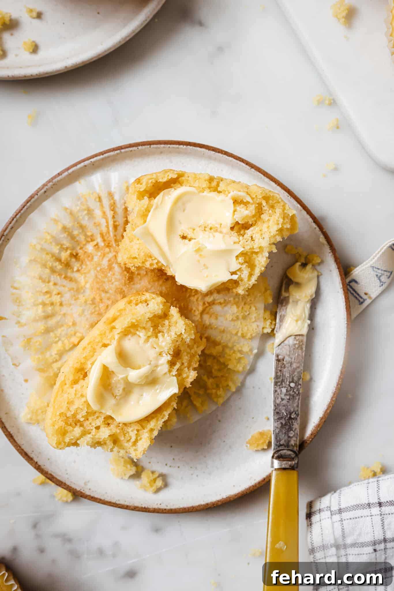 Close up of a buttered cornbread muffin.