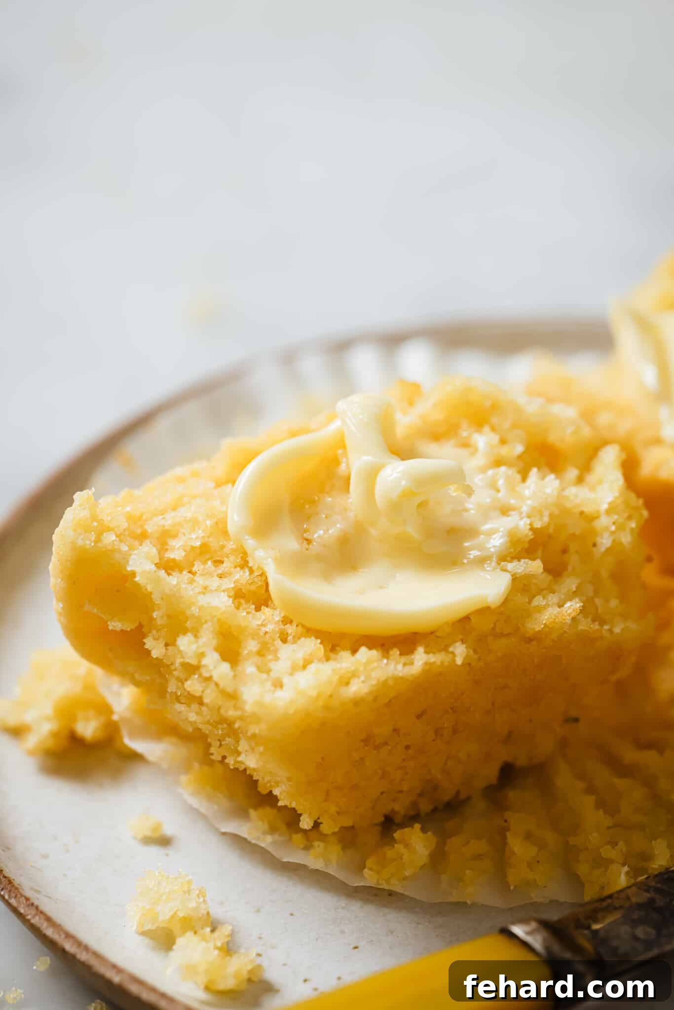 Close up of a buttered cornbread muffin.