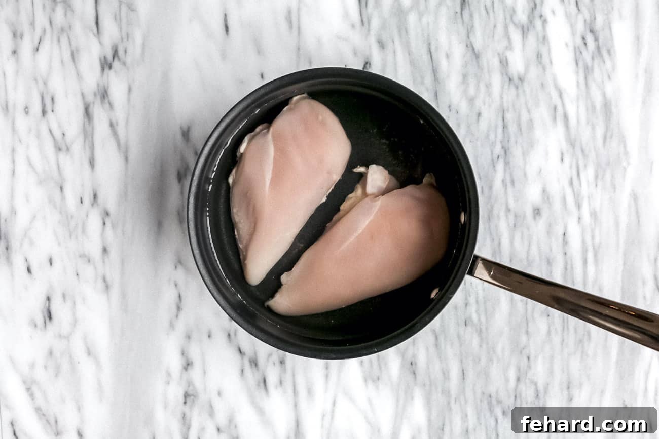 Chicken poached in a small pan.