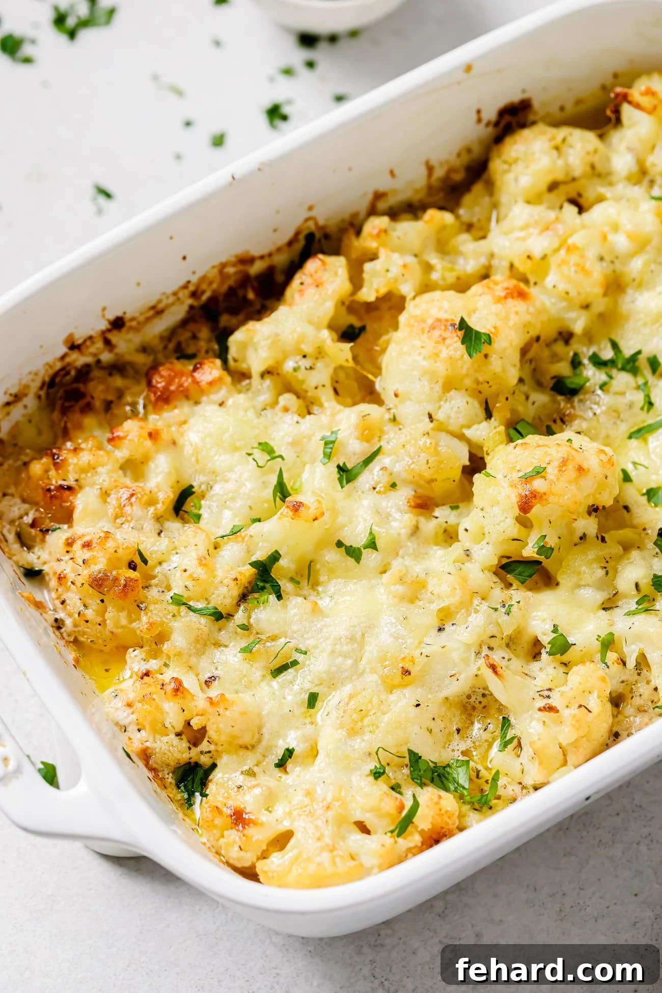Close up of cauliflower au gratin in a baking dish, golden and bubbly.