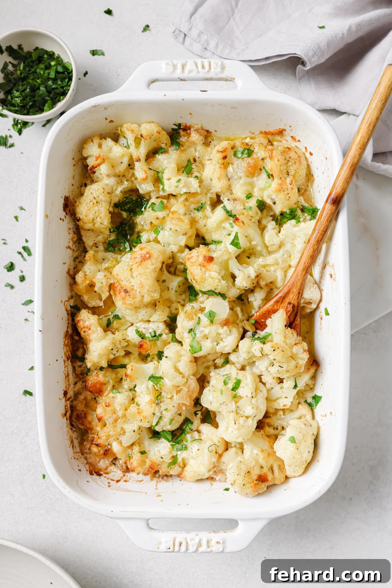 Close up of a golden, bubbly cauliflower au gratin in a baking dish.
