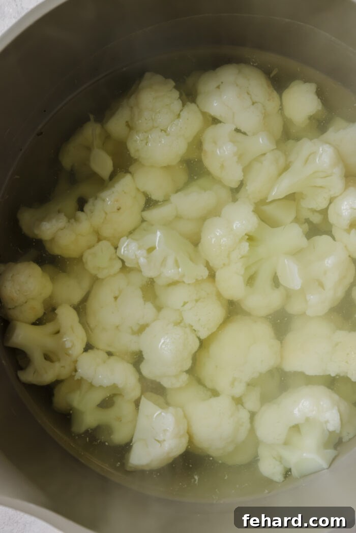 Cauliflower florets boiling in a pot of water.