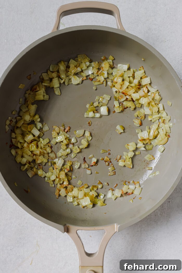 Chopped onions sautéing in a skillet with olive oil.
