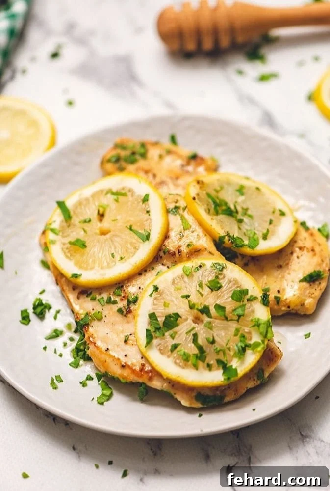 Lemon Chicken Honey Plated Honey Lemon Chicken on a white dish, garnished with fresh lemon wedges and chopped parsley.
