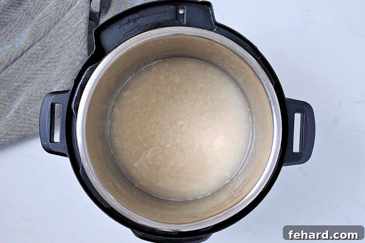Rinsed white rice and the correct amount of water inside the inner pot of an Instant Pot, ready for cooking.