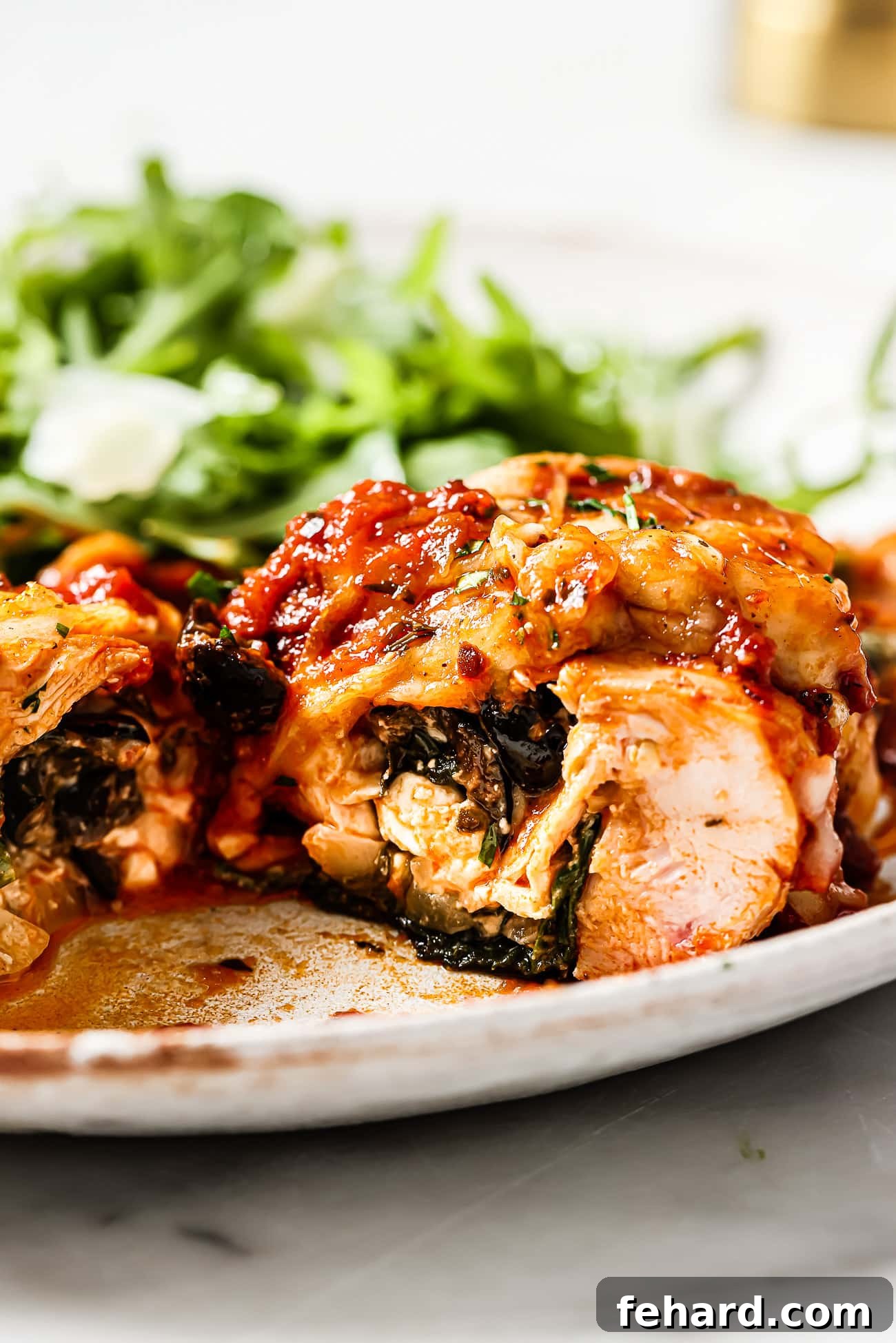 A closeup of spinach and feta stuffed chicken on a white plate.