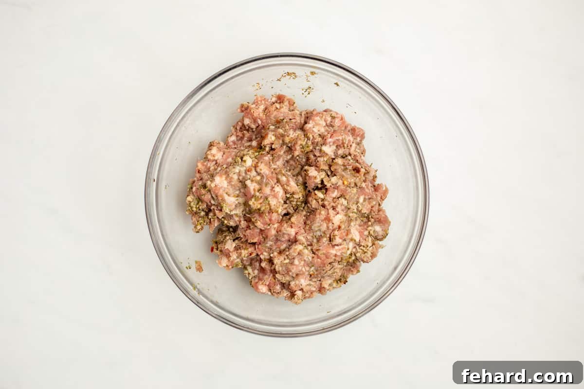 How to Make Italian Sausage from Scratch Ground Pork mixed with a vibrant array of spices to make Italian sausage, ready for chilling and cooking.