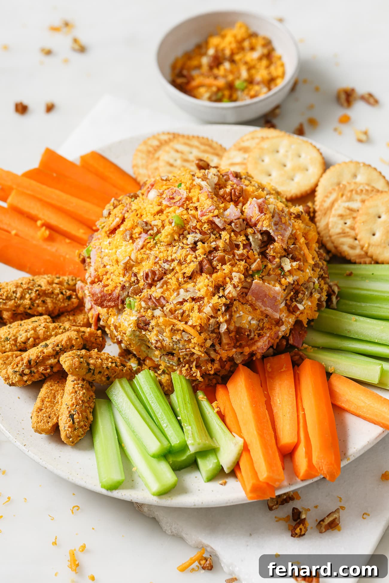 Cheese Ball on a plate with vegetables, crackers, and bread sticks. 