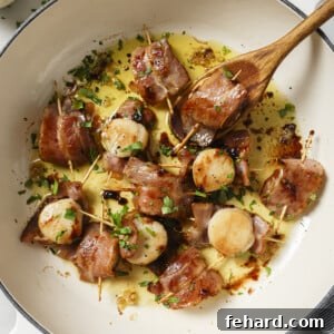 A plate of freshly cooked Bacon Wrapped Scallops garnished with parsley and lemon.