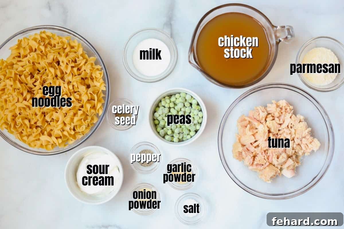 Arrangement of ingredients for homemade tuna noodle casserole on a kitchen counter, including egg noodles, cans of tuna, chicken stock, sour cream, and peas.