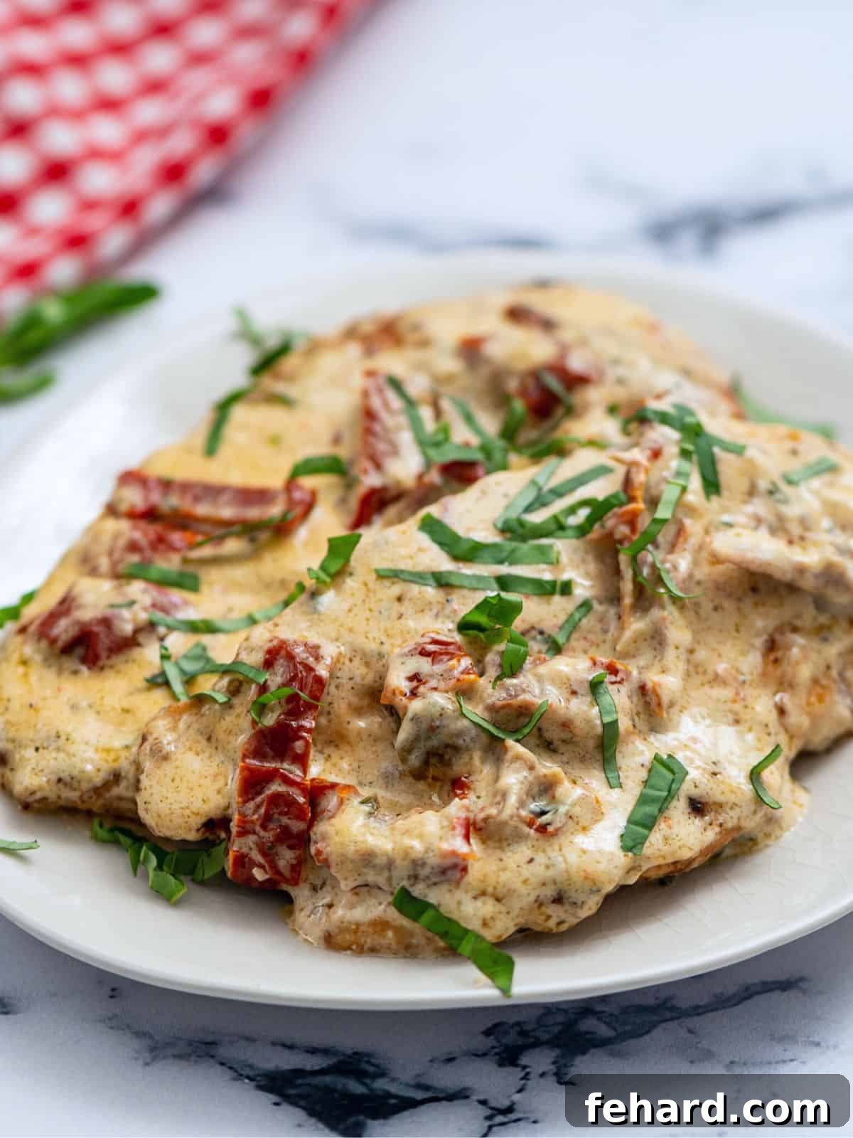 Marry Me Chicken with Creamy Sun-Dried Tomato Sauce Two perfectly pan-seared chicken cutlets generously covered in a rich, creamy sun-dried tomato parmesan sauce, served on a white plate, ready to be enjoyed.