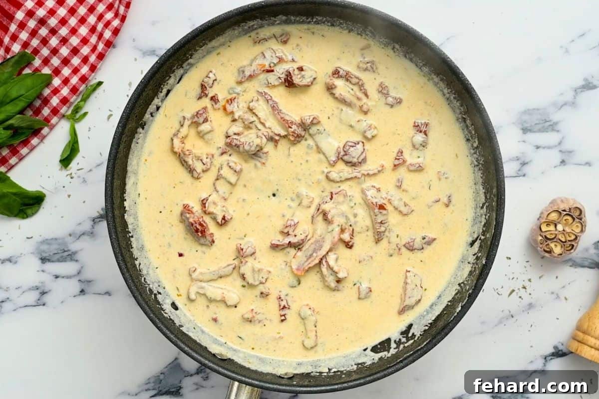 Sun-Dried Tomato Cream Sauce for Chicken A vibrant, creamy parmesan sauce simmering in a skillet, studded with bright sun-dried tomatoes, forming the base for the Marry Me Chicken.