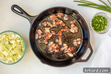 Bacon in skillet after browning with cabbage on the side.