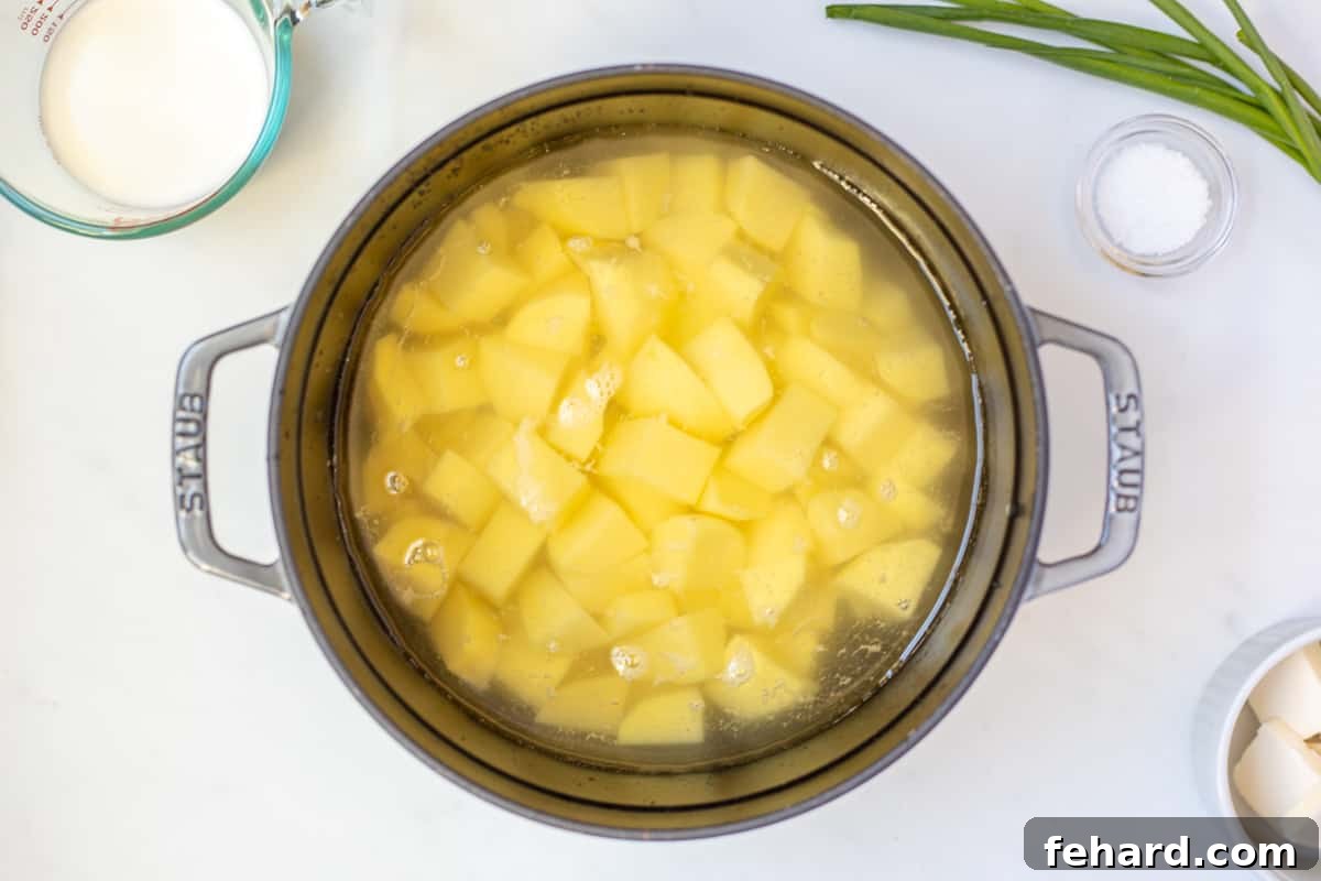 Cubed potatoes submerged in water in a Dutch oven, ready for boiling.