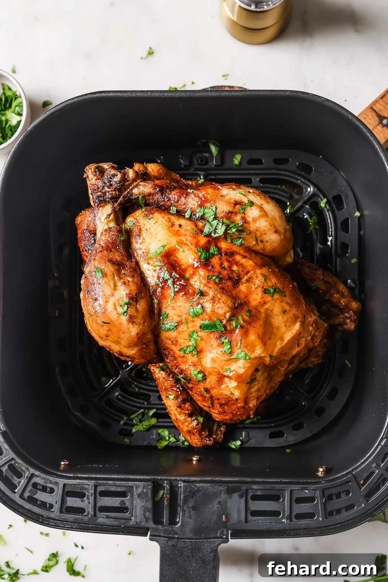 A cooked whole chicken in the air fryer, presented beautifully.