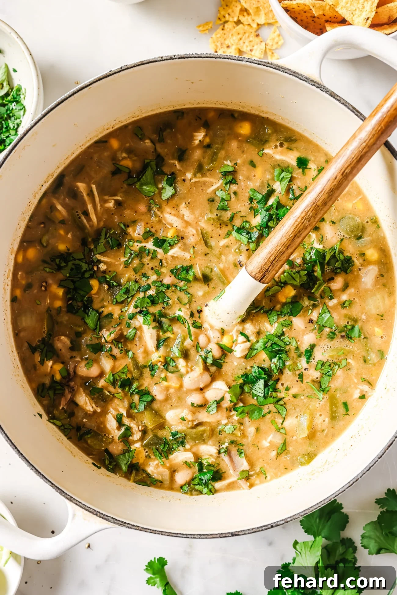 White Chicken Chili served in a rustic Dutch oven, garnished generously with fresh cilantro.