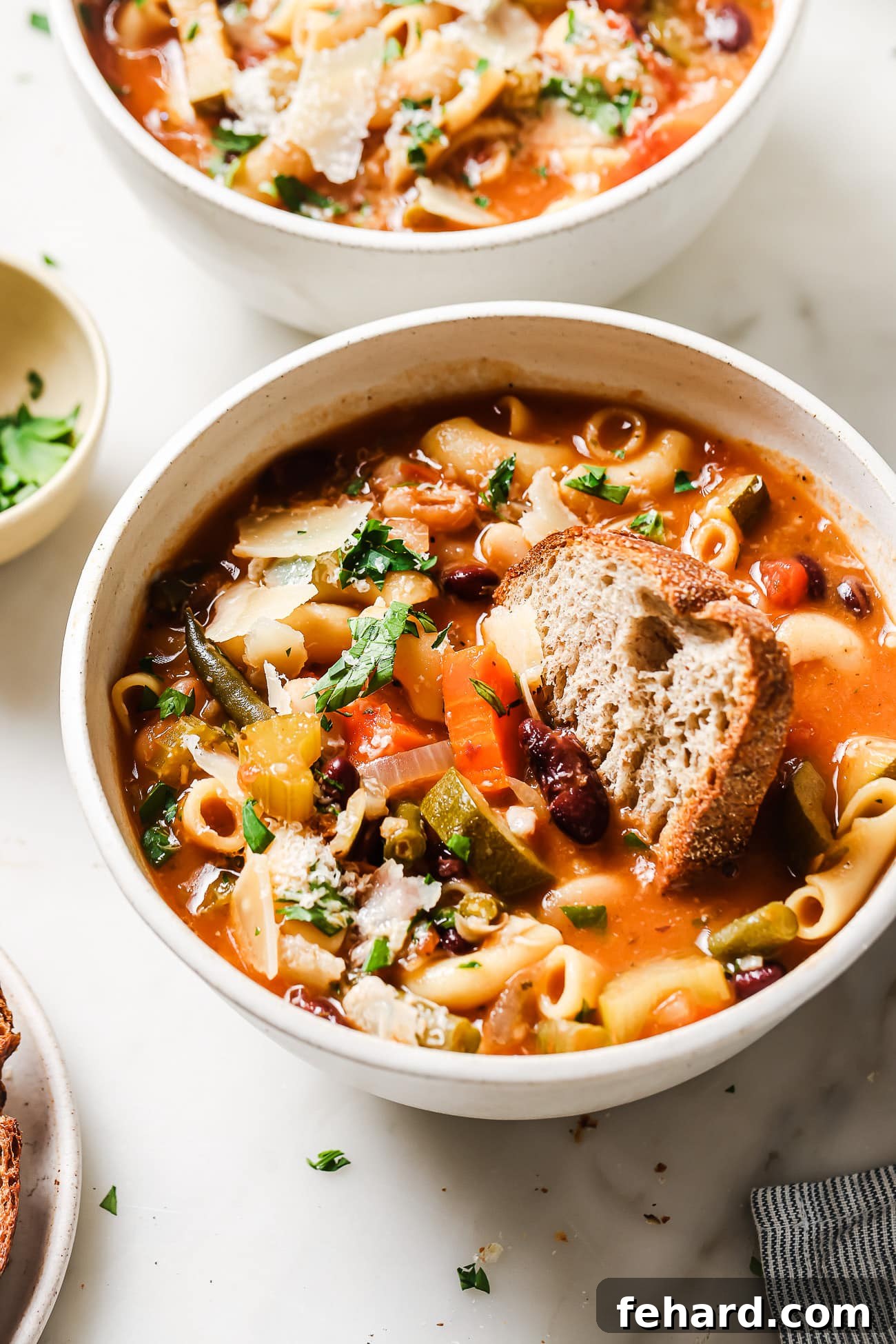 Hearty Vegetable Minestrone 8 A comforting bowl of Minestrone Soup with a slice of fresh bread, ready to be enjoyed, highlighting the rich texture and vibrant colors of the soup.