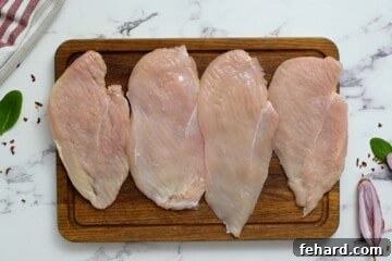 Creamy Florentine Chicken 3 Four chicken cutlets on a wooden cutting board, uniformly pounded and ready for the next step.