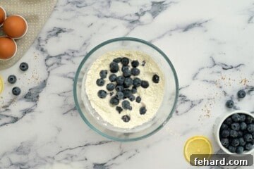 Fresh blueberries coated in flour mixture in a bowl, ready to be added to the coffee cake batter.