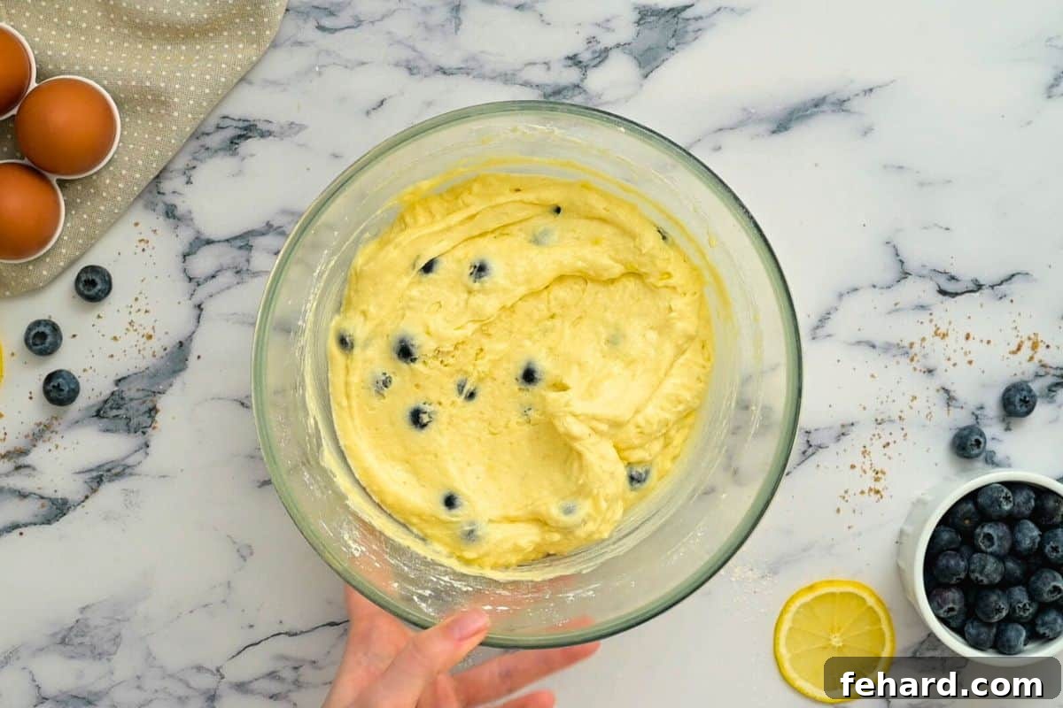 Lemon Blueberry Coffee Cake batter in a large mixing bowl, with fresh lemons and blueberries artfully arranged on the side, highlighting the key flavors.