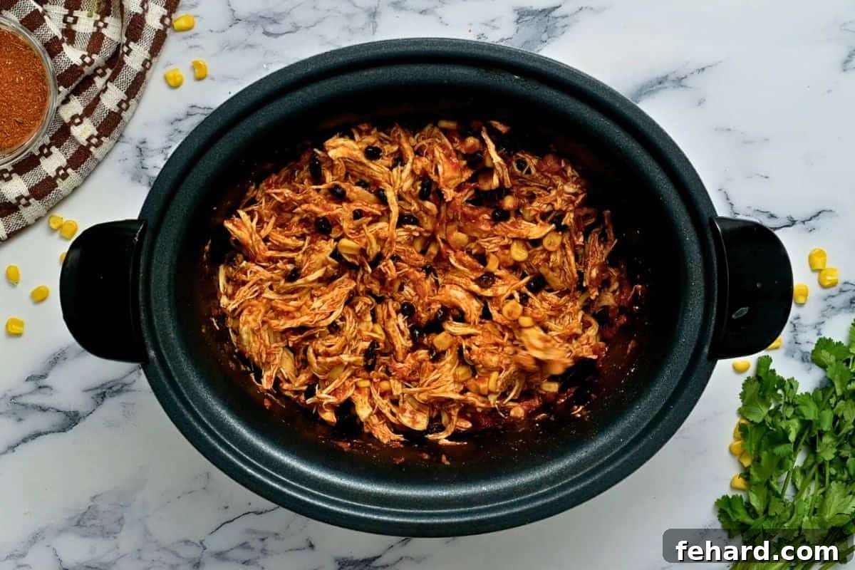 Shredded chicken perfectly mixed into the crockpot with black beans, corn, and salsa, ready to be served.