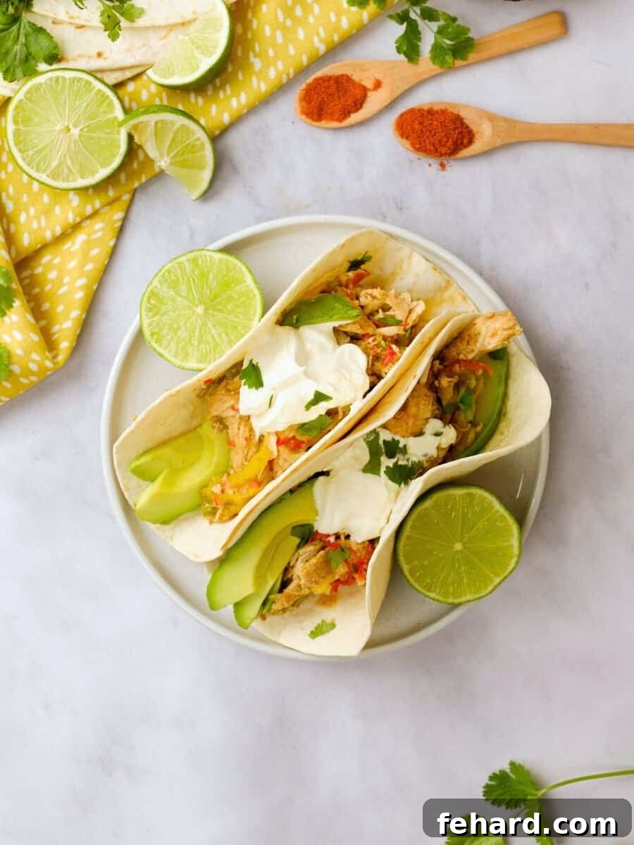 Assembled chicken fajitas made with Instant Pot Chicken Fajita mixture on a plate, garnished with fresh lime wedges and cilantro in the background.