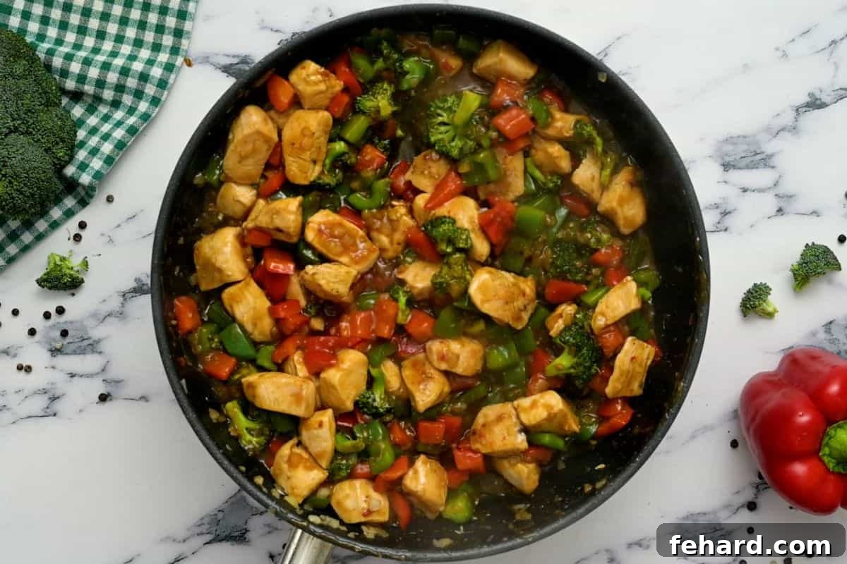 Chinese Chicken Stir Fry Recipe A large sauté pan filled with the completed Hunan Chicken stir-fry, vibrant with cooked chicken and vegetables bathed in a glossy, thickened sauce.