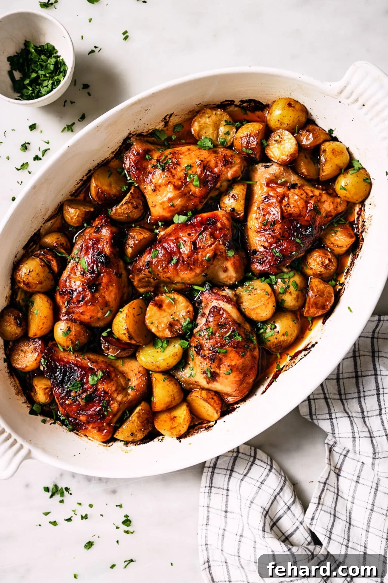 One-Pan Garlic Herb Chicken and Potatoes 7 Leftover chicken thighs and roasted potatoes neatly arranged in a white baking dish, ready for storage or reheating.