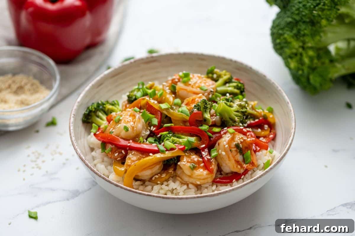 Best Shrimp Stir Fry Recipe A bowl of shrimp stir fry generously served over fluffy white rice, garnished with sesame seeds, showcasing a delicious and healthy meal.